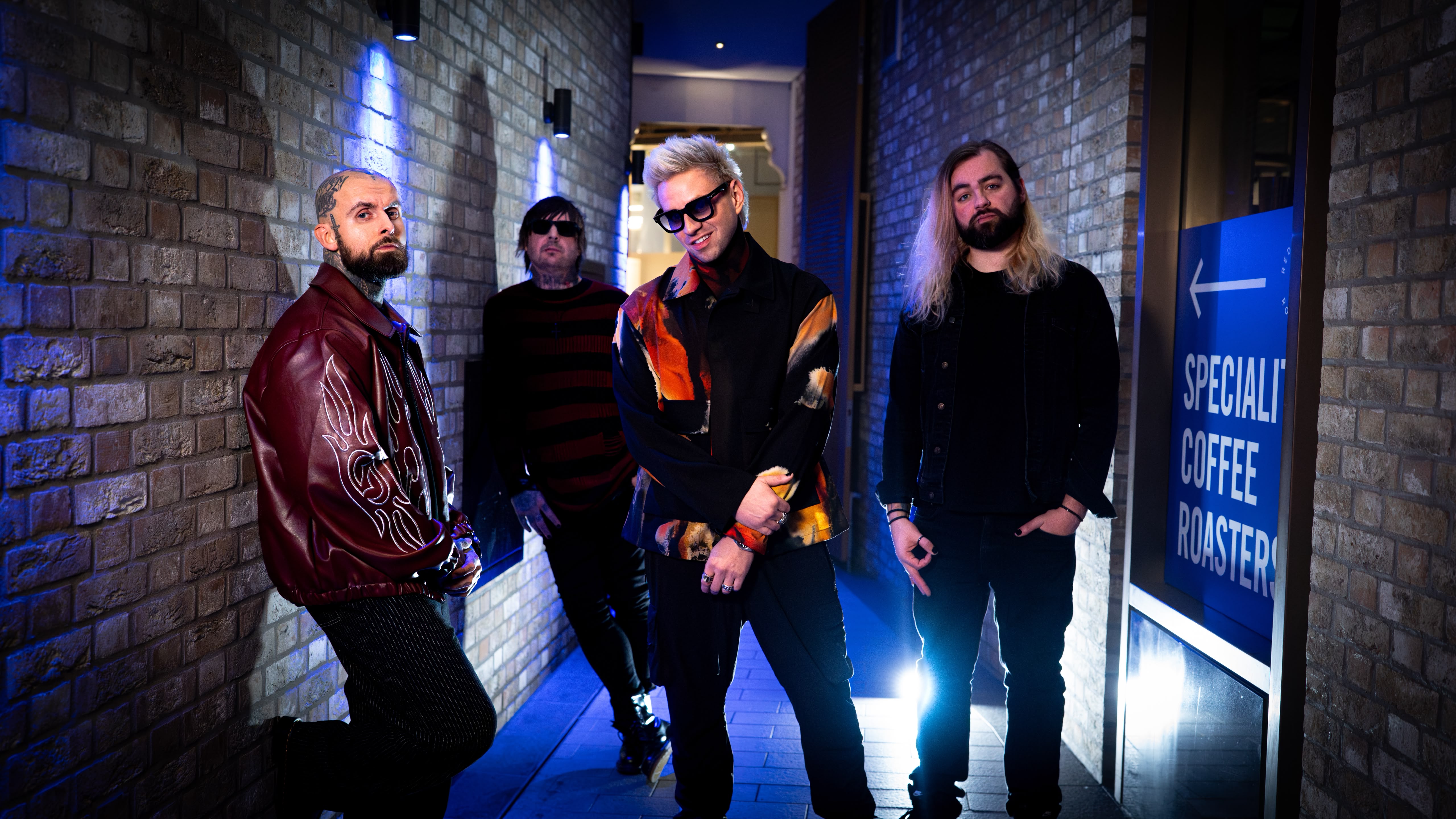 Call Me Amour, the four-piece band, lit in cold blue neon in a brick corridor